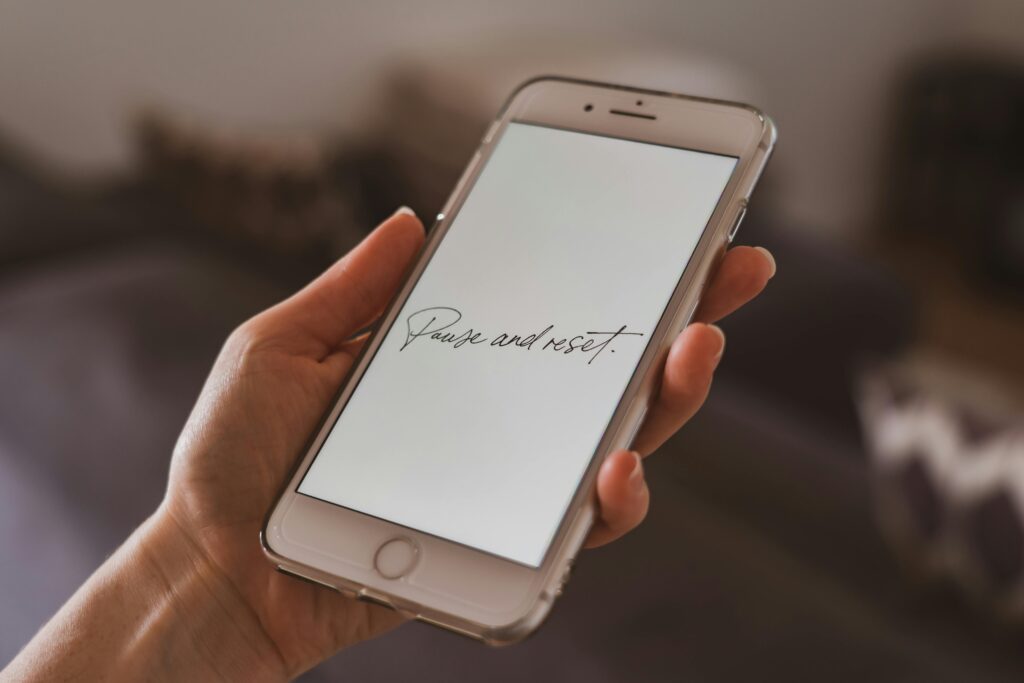 A hand holding a smartphone with a motivational quote on the screen, suggesting reflection.